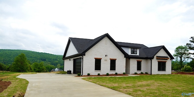 modern farmhouse style home featuring concrete driveway, a front yard, and brick siding