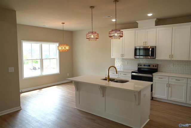 kitchen with backsplash, appliances with stainless steel finishes, light wood finished floors, and a sink