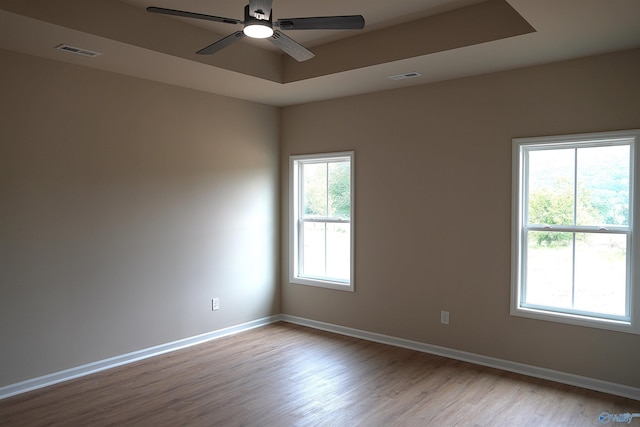 empty room featuring visible vents, ceiling fan, wood finished floors, and baseboards
