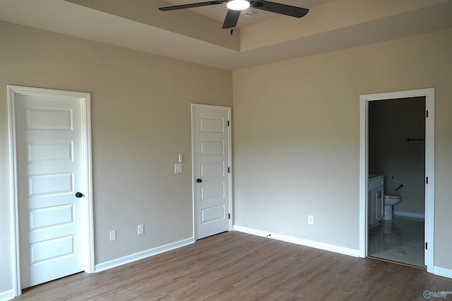 unfurnished bedroom featuring wood finished floors, connected bathroom, and baseboards