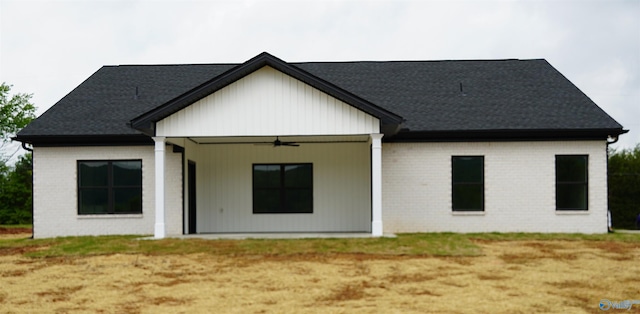 back of property with a shingled roof, brick siding, and a ceiling fan
