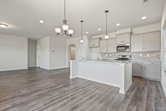 kitchen featuring decorative light fixtures, gray cabinetry, an island with sink, and appliances with stainless steel finishes