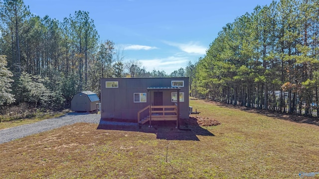 view of front facade featuring a front yard and a storage shed