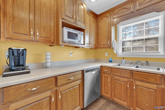 kitchen featuring a sink, brown cabinetry, light countertops, white microwave, and dishwasher