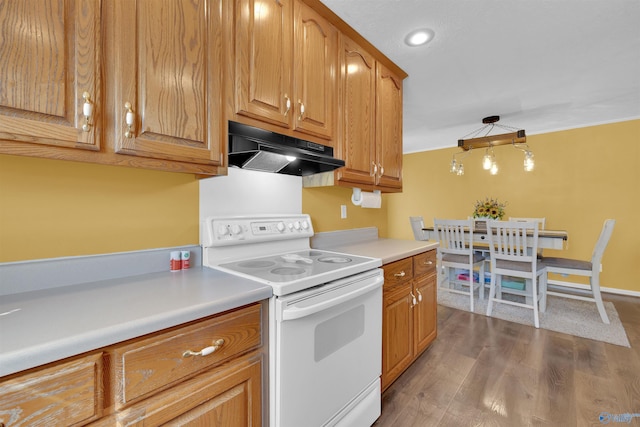 kitchen with under cabinet range hood, light countertops, wood finished floors, brown cabinetry, and white electric range