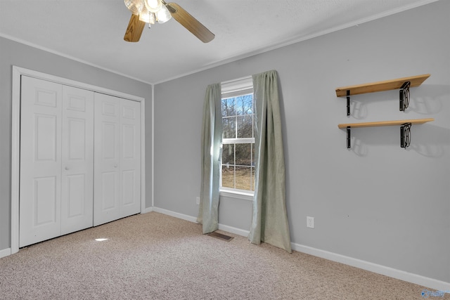 unfurnished bedroom featuring visible vents, a closet, carpet flooring, crown molding, and baseboards