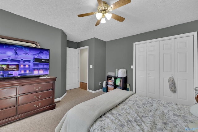 bedroom featuring carpet, baseboards, a ceiling fan, a closet, and a textured ceiling