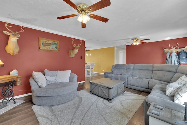 living room with ceiling fan, crown molding, baseboards, and wood finished floors