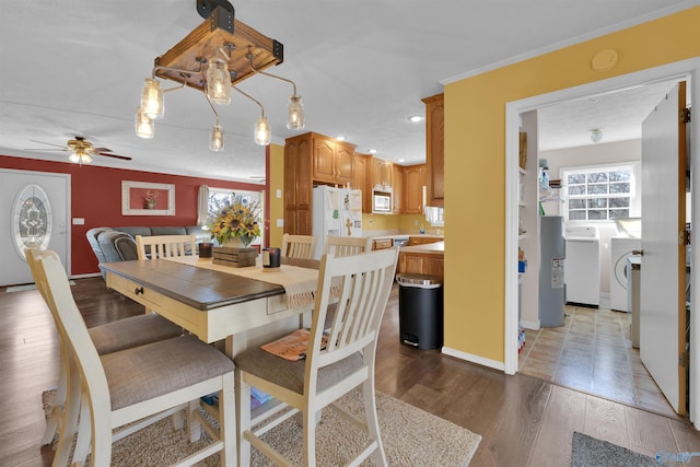 dining area with baseboards, washer and clothes dryer, ornamental molding, wood finished floors, and a ceiling fan