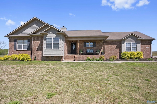view of front of home with a chimney, brick siding, and a front yard