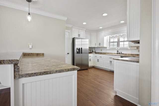 kitchen with white cabinets, stainless steel fridge with ice dispenser, a sink, crown molding, and a peninsula
