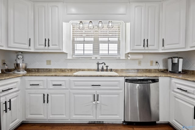 kitchen featuring white cabinets, stainless steel dishwasher, a sink, and tasteful backsplash