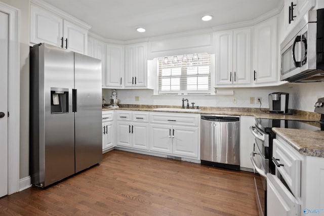 kitchen featuring stainless steel appliances, a sink, recessed lighting, white cabinetry, and dark wood-type flooring