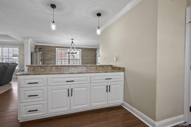 kitchen with a peninsula, open floor plan, baseboards, white cabinetry, and crown molding