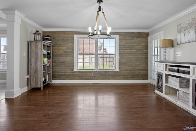 unfurnished dining area featuring baseboards, an inviting chandelier, wood walls, hardwood / wood-style floors, and ornamental molding