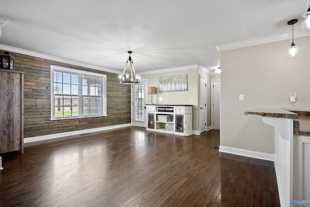 unfurnished dining area featuring crown molding, a chandelier, baseboards, dark wood-type flooring, and visible vents