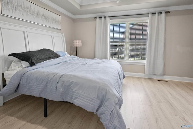 bedroom featuring wood finished floors, crown molding, and baseboards