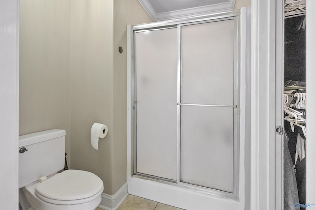 full bath with tile patterned floors, toilet, ornamental molding, baseboards, and a stall shower