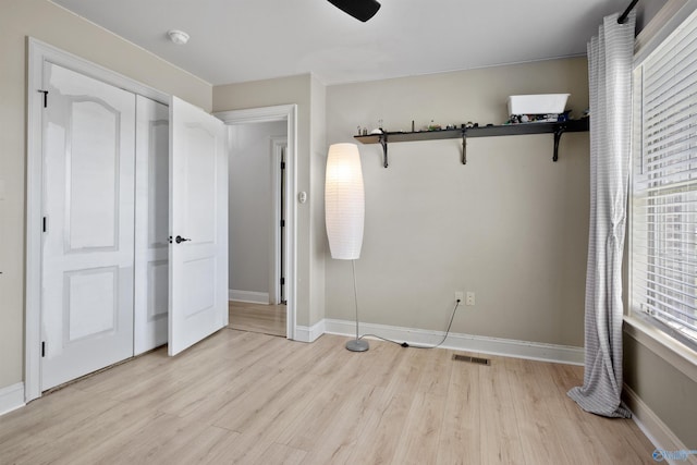 unfurnished bedroom with a closet, light wood-style floors, visible vents, and baseboards