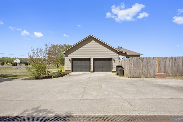 view of side of home featuring concrete driveway and fence