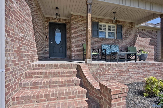 entrance to property featuring brick siding and a porch