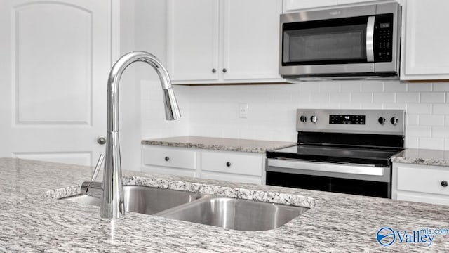 kitchen with light stone countertops, white cabinetry, appliances with stainless steel finishes, and decorative backsplash