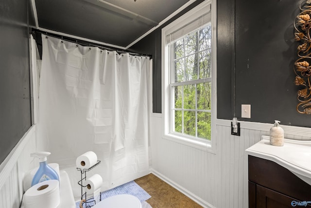 full bath with tile patterned flooring, toilet, curtained shower, and wainscoting