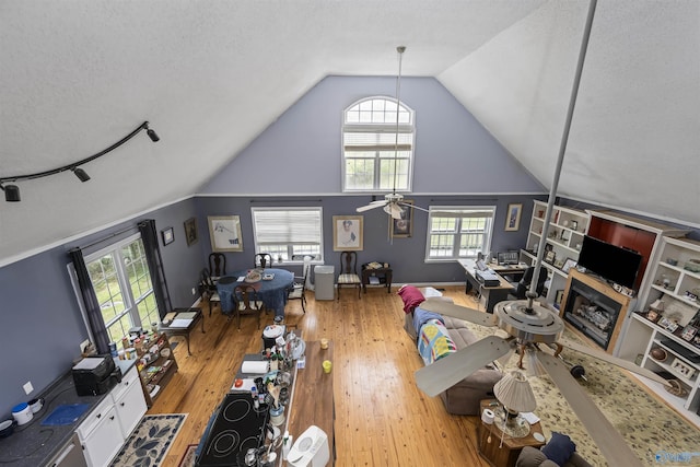 living room with a textured ceiling, wood finished floors, a ceiling fan, and lofted ceiling