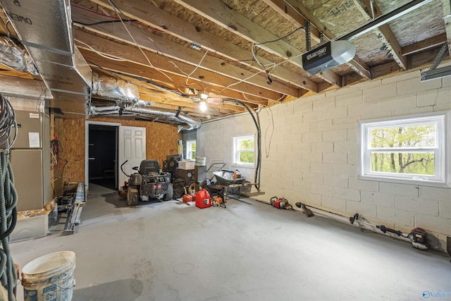 below grade area with a garage, heating unit, and concrete block wall