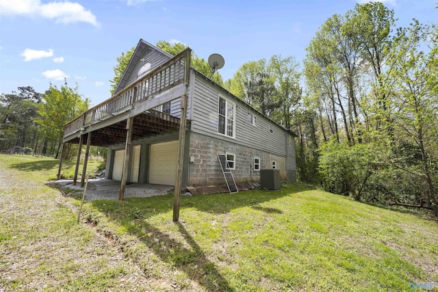 rear view of house with a yard, an attached garage, central air condition unit, a wooden deck, and driveway