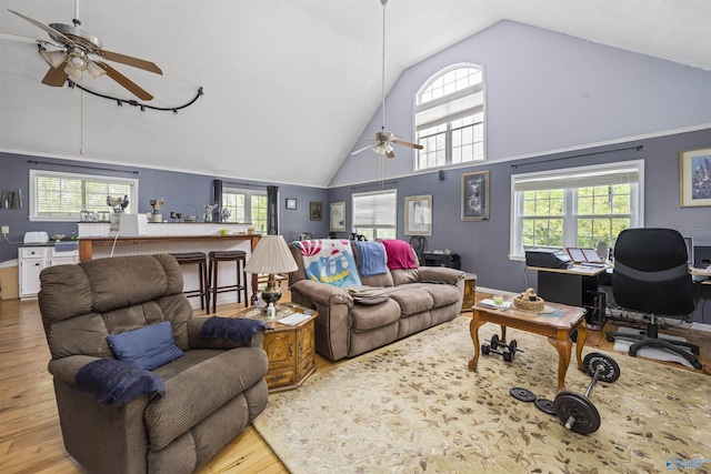 living area with high vaulted ceiling, a ceiling fan, and wood finished floors