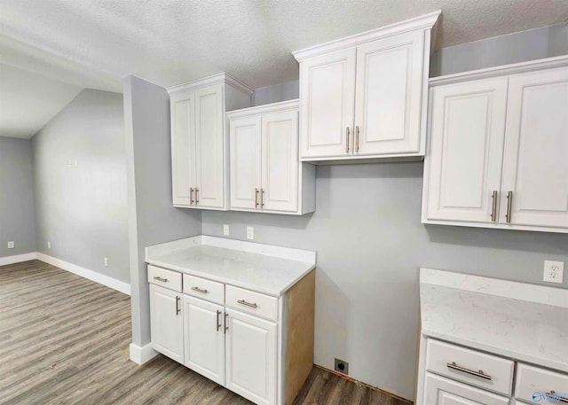 kitchen featuring hardwood / wood-style floors, a textured ceiling, vaulted ceiling, and white cabinets