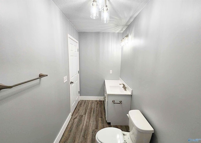 bathroom with hardwood / wood-style flooring, vanity, a textured ceiling, and toilet