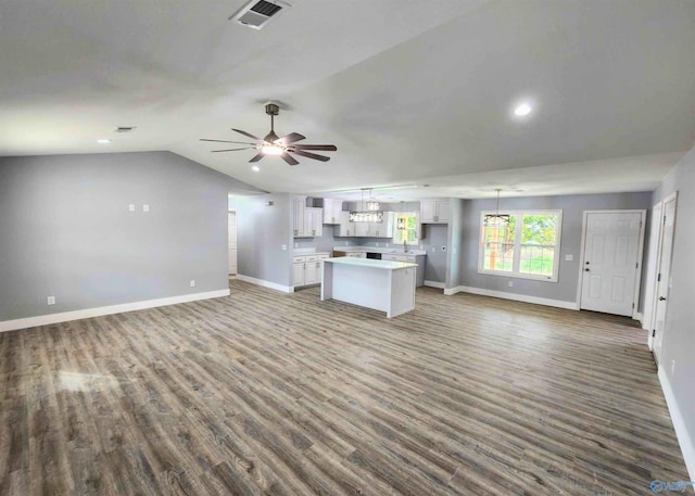 unfurnished living room featuring ceiling fan, dark hardwood / wood-style floors, and vaulted ceiling