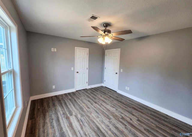 unfurnished room featuring dark wood-type flooring, ceiling fan, and a textured ceiling