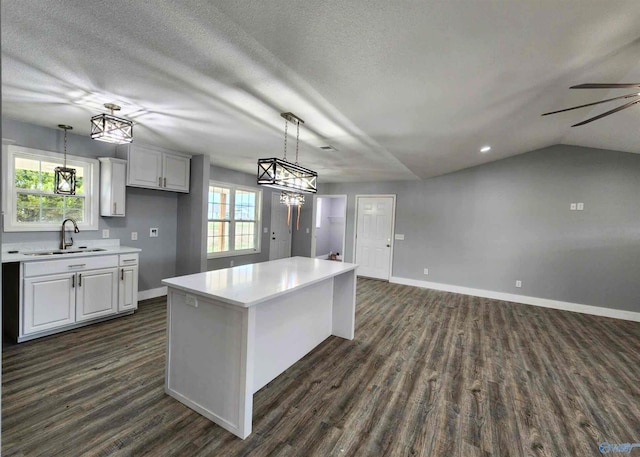 kitchen with hanging light fixtures, a center island, sink, and white cabinets