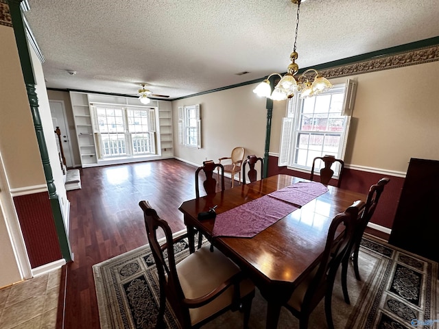 dining room featuring built in shelves, a wealth of natural light, a wainscoted wall, and a textured ceiling