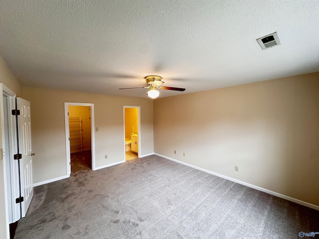 unfurnished bedroom with carpet floors, visible vents, a spacious closet, ceiling fan, and baseboards