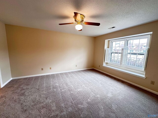 carpeted empty room featuring ceiling fan, a textured ceiling, visible vents, and baseboards