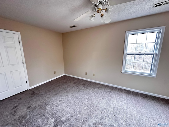 spare room featuring dark colored carpet, visible vents, a textured ceiling, and baseboards