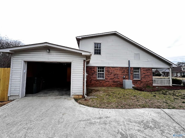 view of home's exterior featuring a garage, central air condition unit, concrete driveway, and brick siding