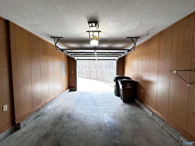 garage with wood walls, electric panel, and a garage door opener