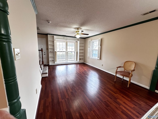 interior space with visible vents, ceiling fan, a textured ceiling, wood finished floors, and baseboards