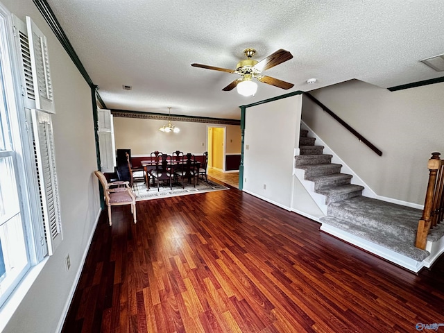 living area featuring visible vents, ornamental molding, a textured ceiling, wood finished floors, and stairs