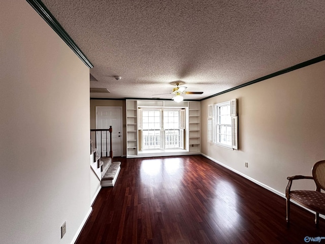 unfurnished living room with crown molding, dark wood-type flooring, a ceiling fan, a textured ceiling, and baseboards