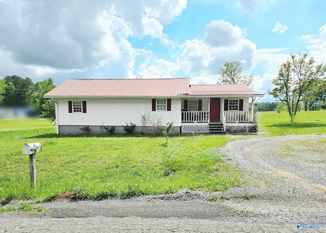 view of front facade featuring a front lawn, covered porch, gravel driveway, and metal roof