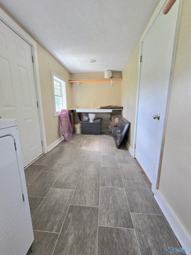 interior space with washer / dryer, baseboards, laundry area, and a textured ceiling