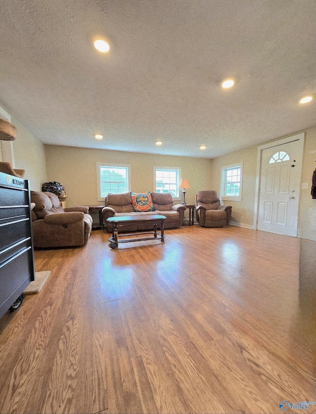 living room featuring a textured ceiling, recessed lighting, and wood finished floors