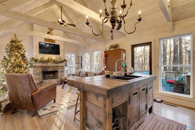 kitchen featuring plenty of natural light, lofted ceiling with beams, sink, and wooden walls