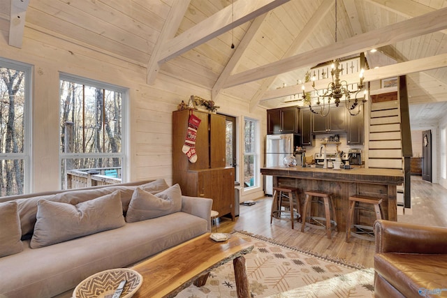 living room featuring light hardwood / wood-style flooring, beamed ceiling, wood walls, a chandelier, and wood ceiling